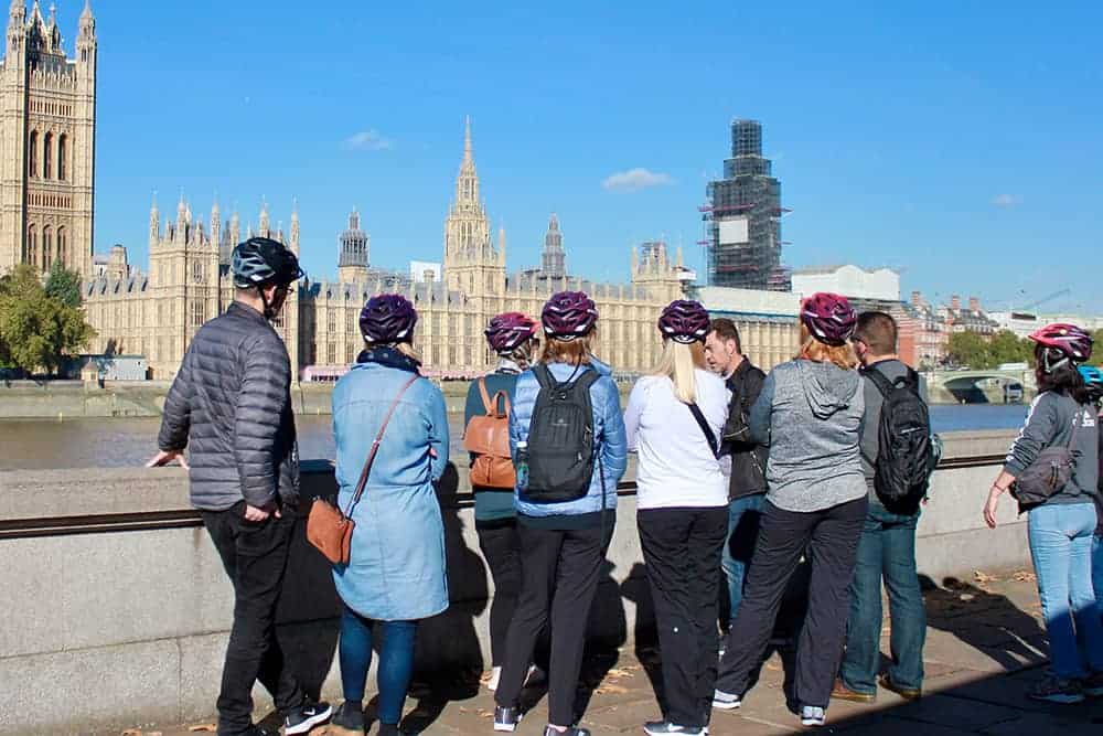 a group on a cycle tour looking across the Thames at the Houses of Parliament