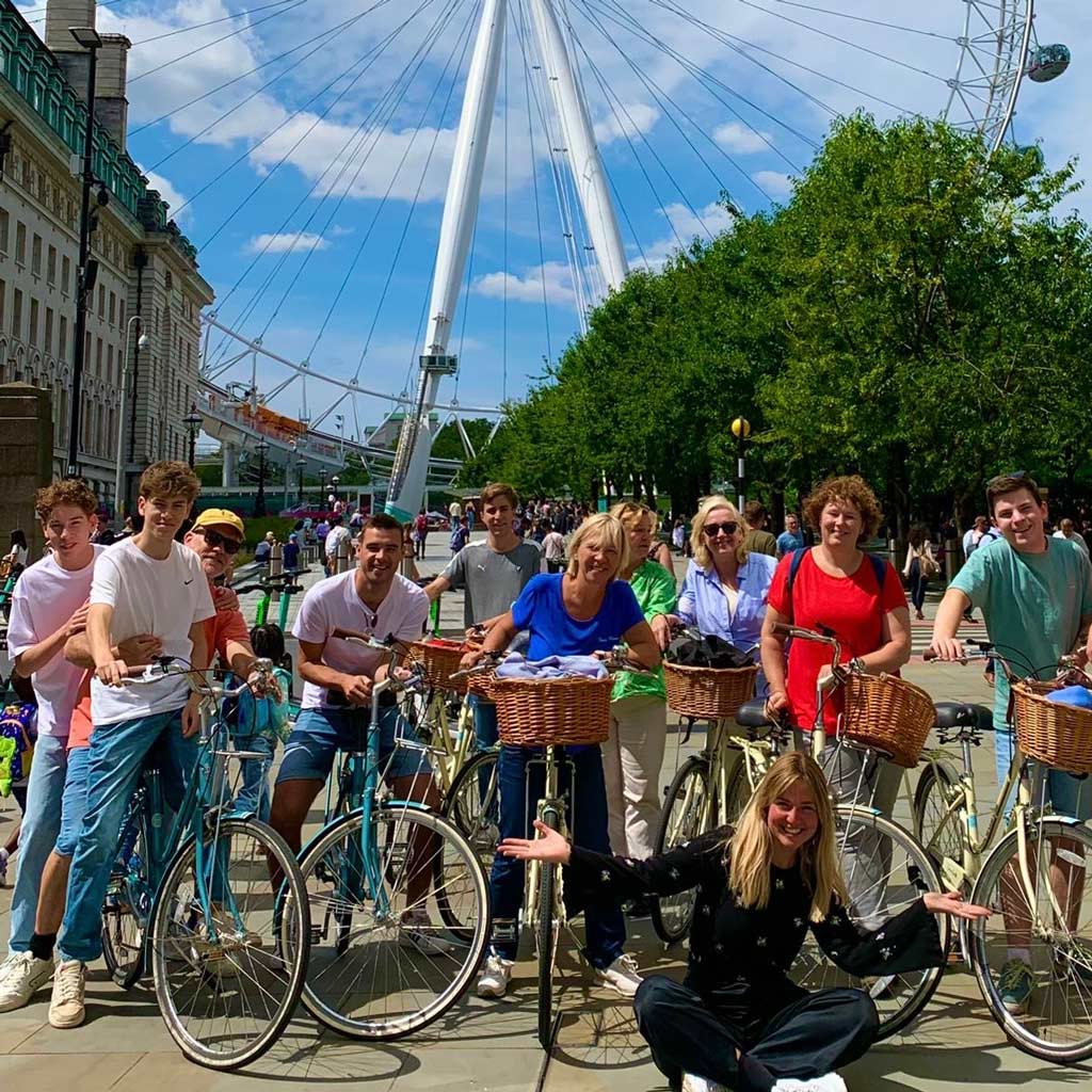 A group of guests visiting from the Netherlands on a Grand London Bike Tour, posing with their guide in front of The London Eye